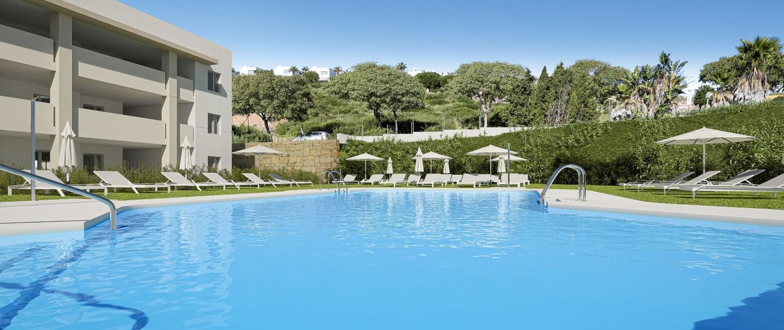 A modern apartment building with balconies overlooks a bright blue swimming pool and loungers on a sunny day.
